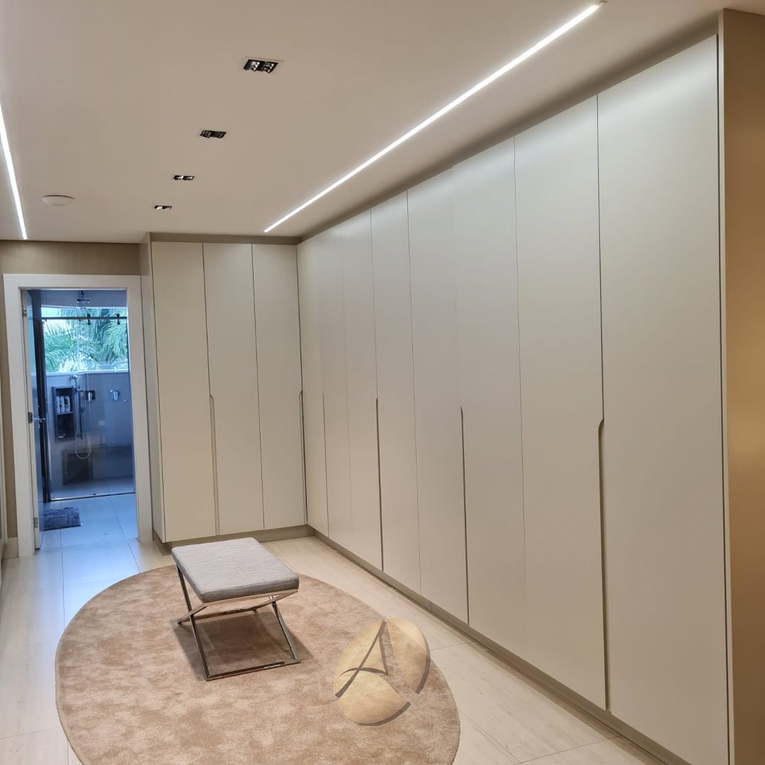 Sala com sofá de couro caramelo, parede de ripado de madeira com pôsteres do Elvis Presley e iluminação de sanca com fita LED