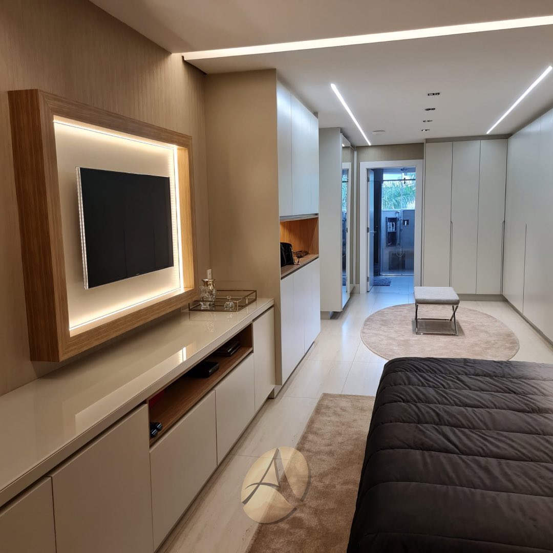 Cozinha gourmet linear com bancadas em mármore Calacatta, cooktop embutido, coifa em aço inox e armários superiores espelhados com iluminação em fita LED